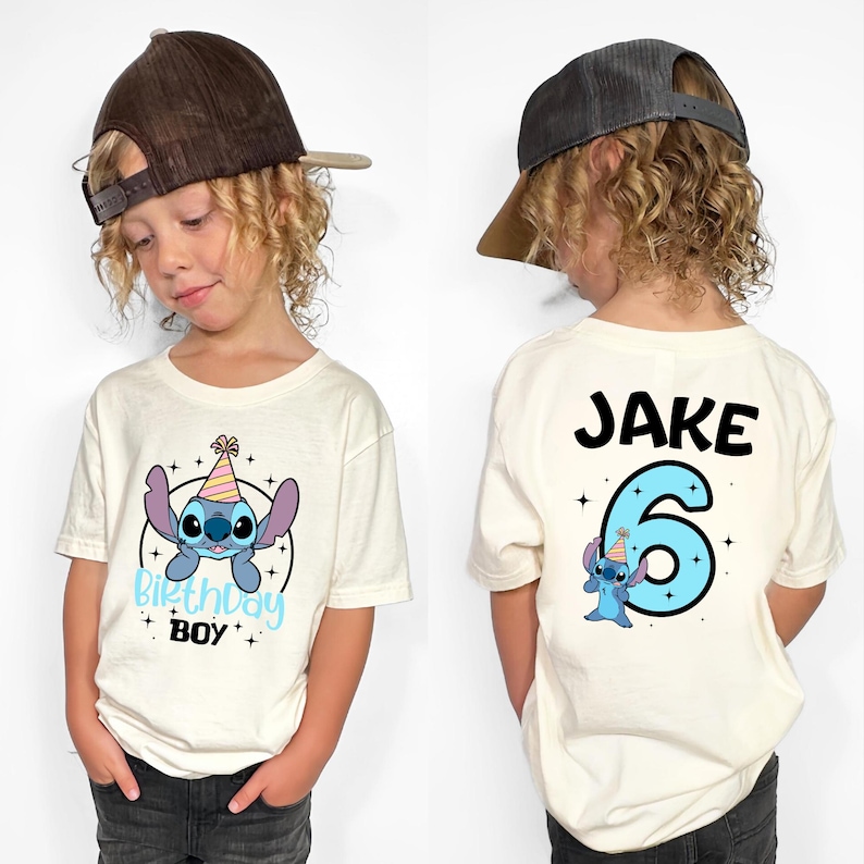K&ouml;nnte beinhalten: Cremefarbenes T-Shirt mit einer Cartoonfigur und dem Text "Birthday Boy" auf der Vorderseite. Auf der R&uuml;ckseite stehen der Name "Jake" und die Zahl "6" mit derselben Cartoonfigur. Das T-Shirt wird von einem Kind getragen.