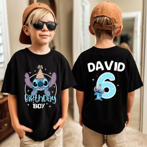 K&ouml;nnte beinhalten: Schwarzes T-Shirt mit einem Cartoon-Stitch-Charakter und dem Text "Birthday Boy" auf der Vorderseite. Auf der R&uuml;ckseite des Shirts stehen der Name "David" und die Zahl "6". Das Design umfasst eine Partyh&uuml;tchen und Sterne.