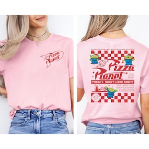 May include: A light pink t-shirt featuring the Pizza Planet logo on the front and back. The back of the shirt has a red and white checkered pattern with the text "Pizza Planet" and images of green aliens. The shirt also has the text "Friday Night Kids Night".