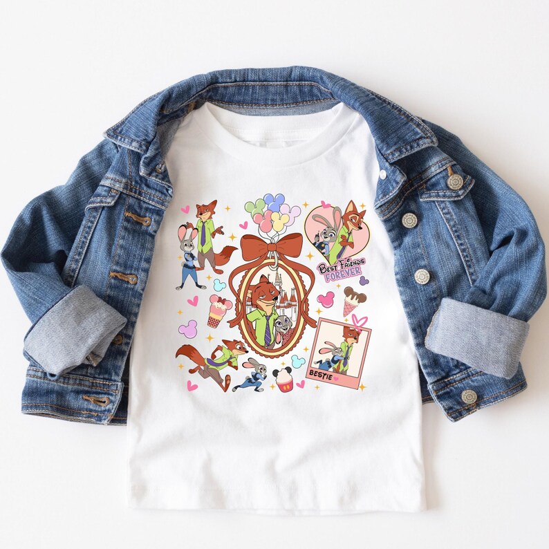 Może przedstawiać: Biała koszulka z postaciami z kresk&oacute;wki Zootopia, w tym Nickiem Wilde i Judy Hopps. Projekt zawiera napisy "Best Friends Forever" i "Bestie", a także serca, rożki lod&oacute;w i balony. Na koszulce jest narzucona dżinsowa kurtka.