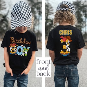 May include: Black t-shirt with "Birthday Boy" text and a cartoon cowboy design. The back of the shirt features the name "CHRIS" and the number "3" with a cowboy theme. The child is wearing a checkered hat and blue jeans.