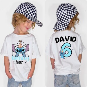 K&ouml;nnte beinhalten: Wei&szlig;es T-Shirt mit einem Cartoon-Stitch-Design und dem Text "Birthday Boy". Auf der R&uuml;ckseite des Shirts stehen der Name "DAVID" und die Zahl "6" mit einer Stitch-Grafik. Das Kind tr&auml;gt eine schwarz-wei&szlig; karierte Baseballkappe.