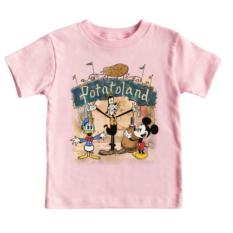 May include: A light pink toddler t-shirt featuring a cartoon graphic of Mickey Mouse, Donald Duck, and Goofy in front of a sign that reads "Potatoland". The characters are in a vintage style.