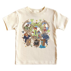 May include: Cream-colored t-shirt featuring a colorful cartoon illustration of characters from Zootopia. The design includes Nick Wilde, Judy Hopps, and other characters within a decorative heart-shaped frame. The shirt is made of a soft, comfortable material.