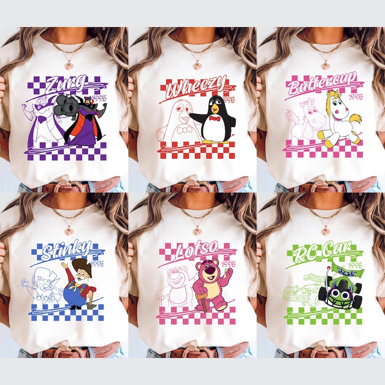 Op de afbeelding: Zes cr&egrave;mekleurige t-shirts met kleurrijke grafische ontwerpen. Elk shirt heeft een ander personage uit een populaire animatiefilm, met tekst boven en onder het personage. De ontwerpen staan tegen een geblokte achtergrond.