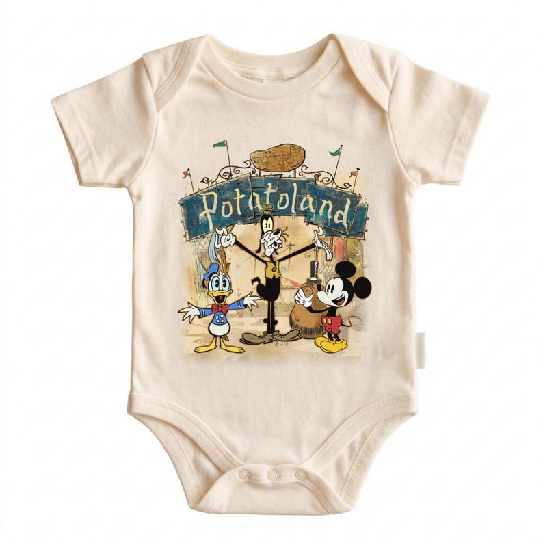 May include: Cream-colored baby bodysuit featuring a colorful graphic of Mickey Mouse, Donald Duck, and Goofy in front of a sign that reads "Potatoland". The design includes a potato and green flags. The bodysuit has short sleeves and a snap closure.