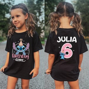 K&ouml;nnte beinhalten: Schwarzes T-Shirt mit einer Cartoonfigur mit Geburtstagshut und dem Text "Birthday Girl". Auf der R&uuml;ckseite des Shirts stehen der Name "Julia" und die Zahl "6" in Rosa, zusammen mit einer passenden Cartoonfigur.