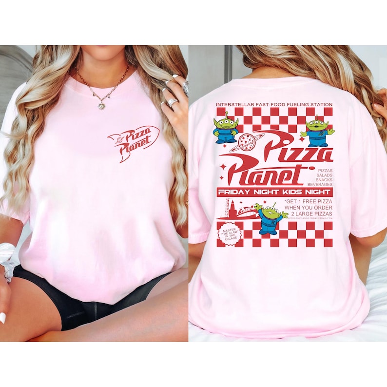 May include: A light pink t-shirt featuring the Pizza Planet logo on the front and back. The back of the shirt has a red and white checkered pattern with the words "Pizza Planet" and "Friday Night Kids Night".