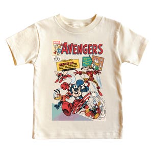 May include: Cream-colored t-shirt featuring a comic book-style graphic of Disney characters as Avengers. The design includes Mickey Mouse as Captain America, Donald Duck, and Iron Man, with text reading "The Avengers" and "What If..."