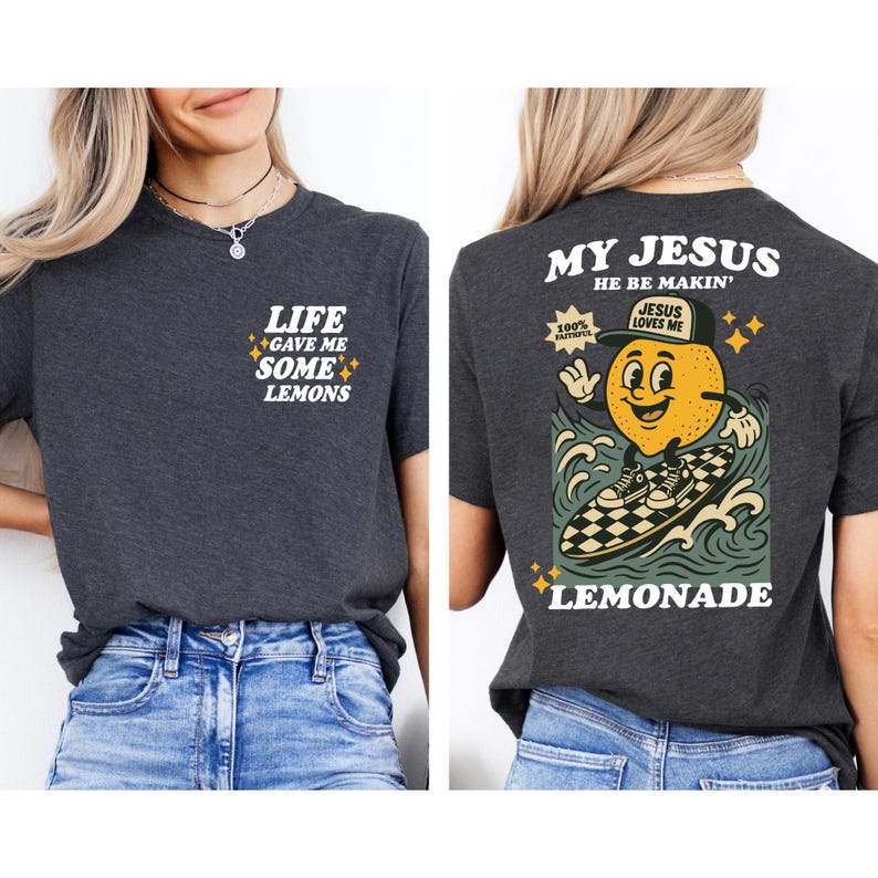 Puede incluir: Camiseta gris oscuro con el texto "LIFE GAVE ME SOME LEMONS" en la parte delantera. La parte trasera presenta un personaje de lim&oacute;n de dibujos animados surfeando en una tabla de surf a cuadros con las palabras "MY JESUS HE BE MAKIN' LEMONADE".