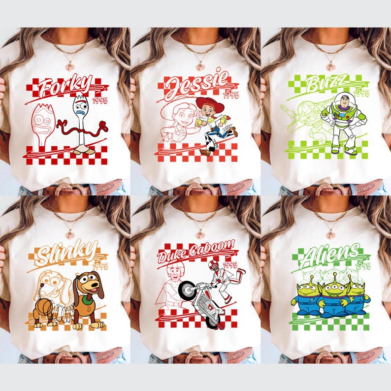 Op de afbeelding: Cr&egrave;mekleurige T-shirts met verschillende Toy Story-personages. Elk shirt heeft een personagenaam in een gestileerd lettertype, een afbeelding en het jaar 1995. Personages zijn Forky, Jessie, Buzz, Slinky, Duke Caboom en Aliens.
