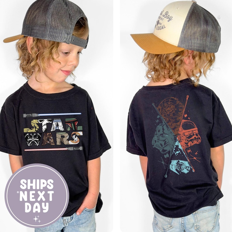 May include: Black Star Wars t-shirt featuring the Star Wars logo and characters on the front and back. The front design includes the Star Wars logo with lightsabers. The back design features Darth Vader, a Stormtrooper, and other characters.