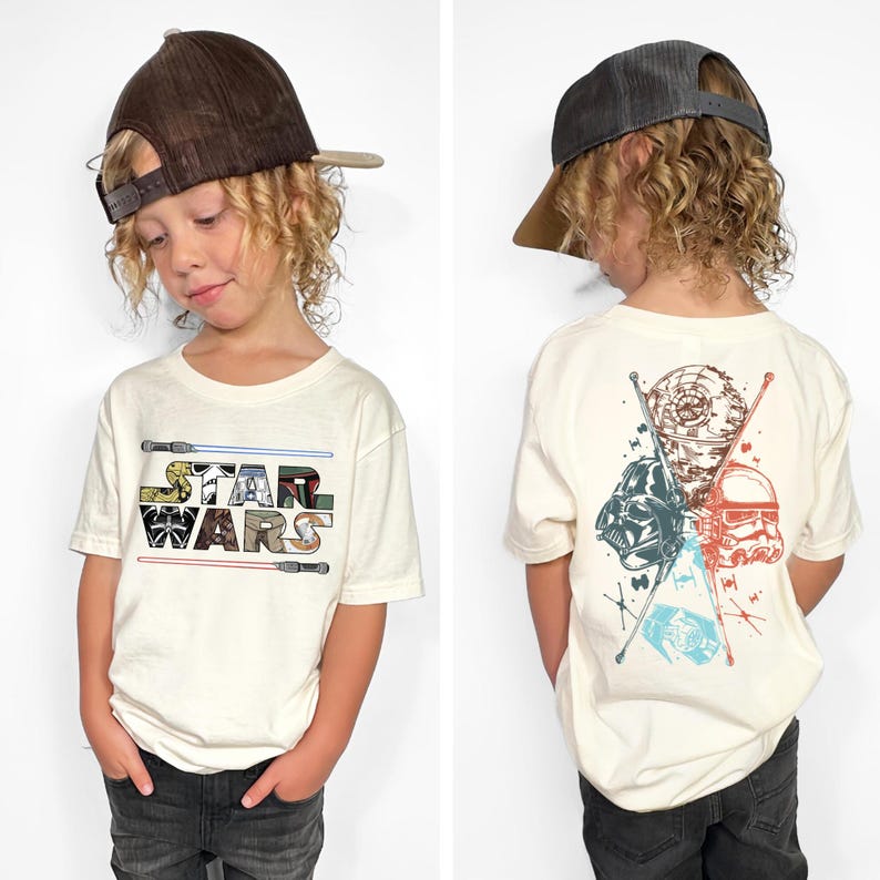 May include: Off-white Star Wars t-shirt with the Star Wars logo on the front and a graphic of characters on the back. The front logo features a colorful design. The back graphic includes Darth Vader, a Stormtrooper, and the Death Star.