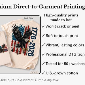 Pode incluir: Uma t-shirt cor de marfim com um gr&aacute;fico de uma &aacute;guia-de-cabe&ccedil;a-branca voando sobre uma bandeira americana desgastada e o texto 1776-2026. A imagem mostra as vistas frontal e traseira, destacando a impress&atilde;o direta, tinta suave ao toque, cores vibrantes e algod&atilde;o cultivado nos EUA.