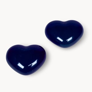 May include: Two glossy, heart-shaped objects in a deep navy blue hue. The hearts are smooth and reflect light, suggesting a polished surface. The objects are set against a plain white background.