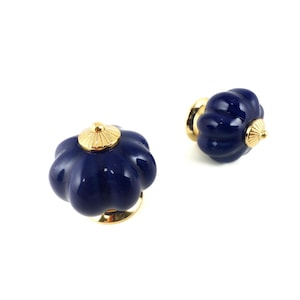 Könnte beinhalten: Zwei marineblaue Keramik-Schrankknöpfe mit Kürbisform und goldfarbener Hardware. Die Knöpfe befinden sich auf weißem Hintergrund. Die Knöpfe sind für Möbel und Heimdekoration.