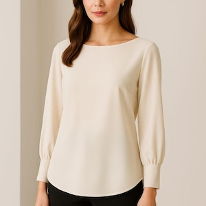 May include: Cream-colored long-sleeve blouse with a boat neckline and fitted cuffs. The blouse has a slightly curved hemline and is paired with black pants. The sleeves are gathered at the cuffs. The top is made of a smooth, opaque fabric.