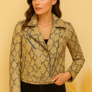 May include: A tan and black snakeskin-patterned jacket with a notched collar, asymmetrical zipper closure, and a belted waist. The jacket is worn with black pants. The overall style is a modern, edgy look.