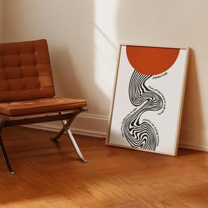 May include: A framed vertical wall art print featuring a large solid orange circle at the top and a black and white wavy, distorted line pattern below. The text reads: John 7:38, He who believes in Me, out of his heart will flow rivers of living water.