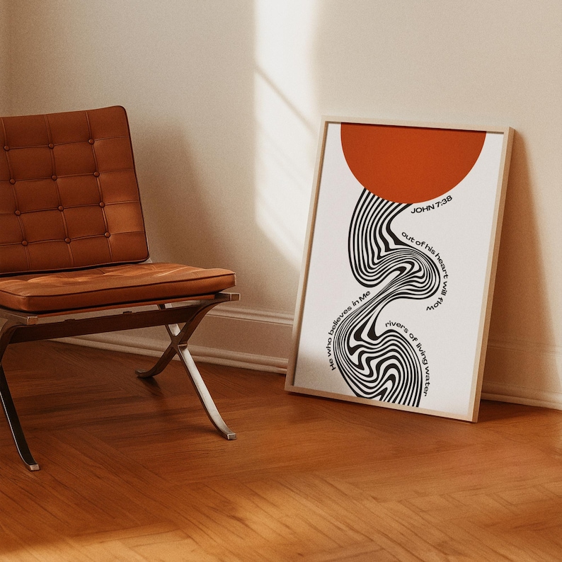 May include: A framed vertical wall art print featuring a large solid orange circle at the top and a black and white wavy, distorted line pattern below. The text reads: John 7:38, He who believes in Me, out of his heart will flow rivers of living water.