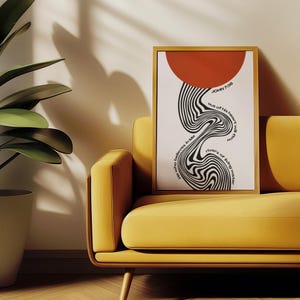 May include: A framed vertical wall art print featuring a solid red circle at the top and a black and white wavy, distorted line pattern flowing downwards. The text reads: "He who believes in Me out of his heart will flow rivers of living water" and "JOHN 7:38".
