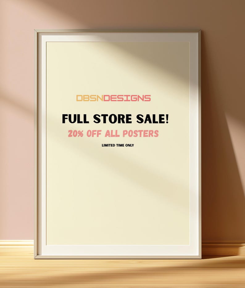 May include: A framed poster with the text "DBSNDESIGNS FULL STORE SALE! 20% OFF ALL POSTERS" in a white frame. The poster is on a light yellow background. The text is in a mix of orange and pink. The frame is leaning against a pink wall.