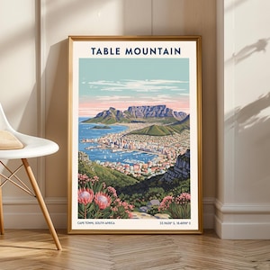 May include: A framed print depicting Table Mountain in Cape Town, South Africa. The artwork shows the mountain, city, and harbour in detail, with a blue and pink sky. The text "TABLE MOUNTAIN" is at the top of the print.