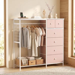 May include: A white metal and pink wardrobe with hanging clothes, drawers, and storage baskets. The wardrobe has a section for hanging clothes, a section with drawers, and a shelf for storage. The drawers are pink with white knobs.