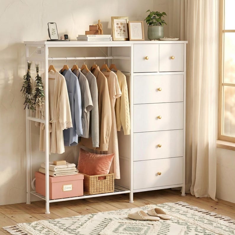 May include: A white metal clothing rack and dresser combination. The rack holds hanging clothes in neutral colors. The dresser has five drawers with gold-colored knobs. Decorative items sit on top, and a rug and slippers are on the floor.