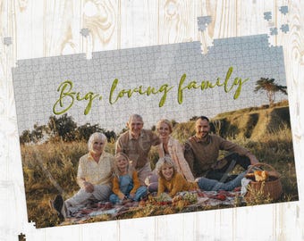 May include: A completed jigsaw puzzle featuring a family picnic scene with the text "Big, loving family" in green script. The puzzle shows a family of six sitting on a blanket with a picnic basket and food.
