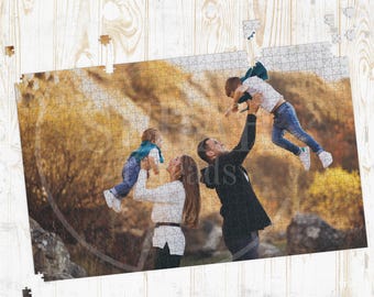 May include: A family portrait puzzle featuring a family of four in an outdoor setting. The puzzle shows a mother and father holding up their two children. The background is a blurred view of trees and foliage. The puzzle is partially assembled.
