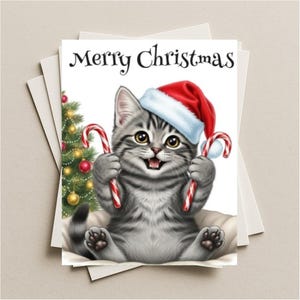 May include: A Christmas card featuring a gray tabby kitten wearing a Santa hat and holding two candy canes. The card reads "Merry Christmas" above the kitten. A decorated Christmas tree is in the background.