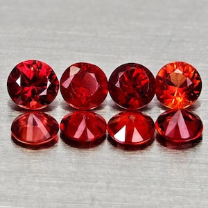 Peut inclure: Huit pierres précieuses rouges, rondes et facettées sont présentées. Les gemmes sont disposées en deux rangées de quatre, la rangée supérieure montrant les gemmes vues du dessus et la rangée inférieure vues de côté. Les gemmes ont un aspect brillant et flamboyant.