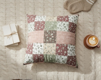 May include: A square throw pillow featuring a patchwork design of floral patterns in shades of sage green, dusty rose, and cream, interspersed with a central horizontal band of pink and white gingham check fabric, creating a multi-textured appearance.