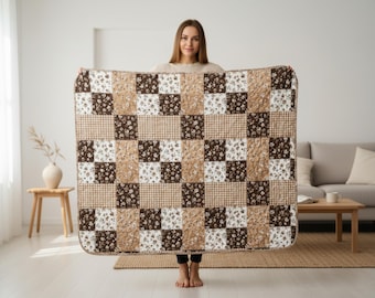 May include: A rectangular quilt featuring a patchwork design of alternating squares. The pattern consists of dark brown squares with a white floral print, white squares with a brown floral print, and light brown squares with a small checkered pattern.