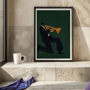 May include: Framed art print showing a musician playing a trumpet. The artwork depicts a person in a dark suit against a dark green background. The trumpet is gold-coloured. The print is displayed on a white ledge, with a white mug.