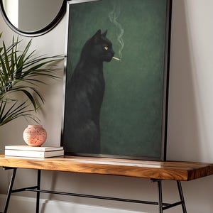 May include: A framed art print depicts a black cat with yellow eyes smoking a cigarette against a green background. The cat is the focal point, with smoke rising from the cigarette. The artwork is displayed on a wooden bench.