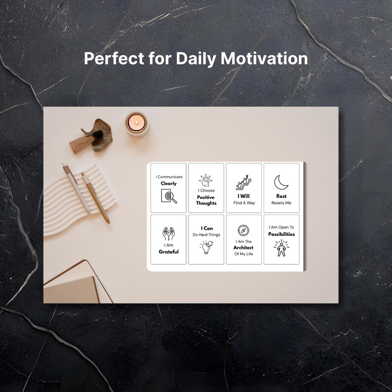 Puede incluir: Una tarjeta rectangular blanca con ocho frases motivacionales e iconos, incluyendo "Me comunico claramente" y "Elijo pensamientos positivos". La tarjeta est&aacute; sobre una superficie beige claro con una vela, bol&iacute;grafos y un bloc de notas.
