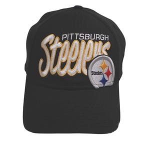 Puede incluir: Una gorra de béisbol negra con la palabra Pittsburgh en letras mayúsculas blancas sobre la palabra Steelers en bordado amarillo grande, cursivo y con borde blanco. Un parche circular con el logo de Steelers está cosido a la derecha.