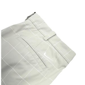 May include: Close-up of light gray golf pants with a white grid pattern. The pants feature a back pocket and a belt loop. A white Nike swoosh logo is visible on the back pocket.