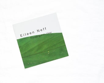 Könnte beinhalten: Ein weißer Buchumschlag mit dem Text "Eileen Neff Traveling into View" in Schwarz gedruckt. Die untere Hälfte des Umschlags ist ein grünes Bild eines Feldes.