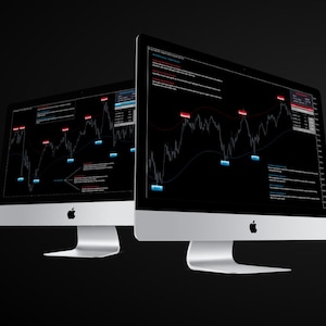 May include: Two silver Apple computer monitors showing financial data charts with red and blue highlights against a black background. The monitors are side-by-side, with the Apple logo visible.
