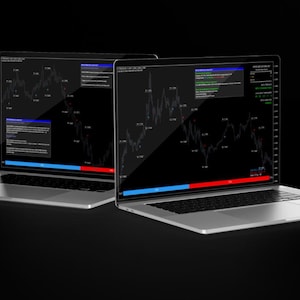 May include: Two silver laptops with screens displaying financial data charts. The screens show a dark interface with white lines and text, and red and blue bars. The laptops are on a black surface.
