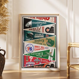 May include: A framed vertical poster featuring a collage of Philadelphia sports team pennants. The design includes logos and text for the Eagles, Phillies, Flyers, and 76ers, highlighting various championship titles and team graphics in red, green, and black.