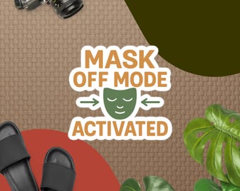 Può includere: Un adesivo con la scritta "MASK OFF MODE ACTIVATED" in marrone e verde. L'adesivo presenta un'icona di maschera verde con frecce. Sono visibili anche infradito nere e una fotocamera.