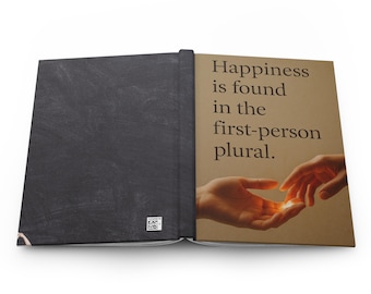 May include: Open journal with a black cover and a tan page with the text "Happiness is found in the first-person plural." The page shows two hands reaching for a glowing light.
