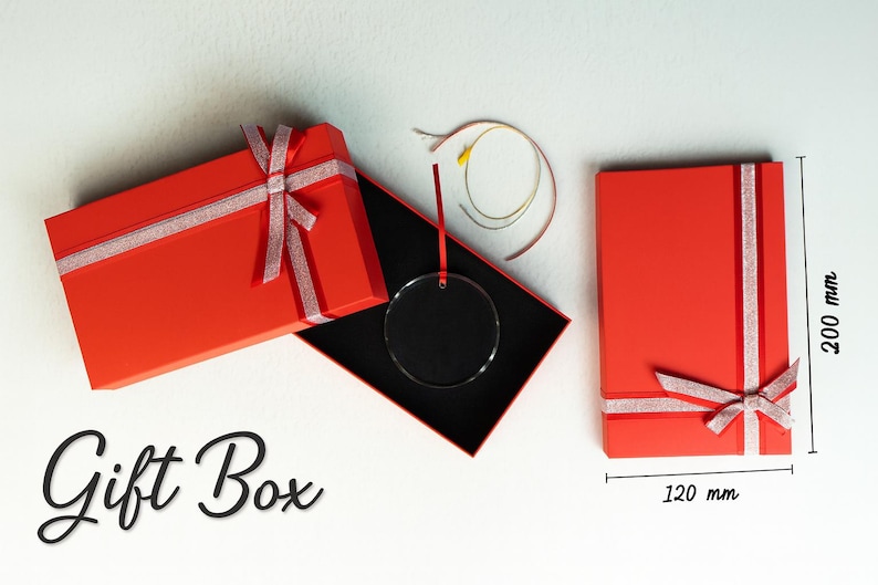 Pode incluir: Caixas de presente vermelhas com fita e la&ccedil;os prateados. Uma caixa est&aacute; aberta, revelando um interior preto e um adorno circular transparente. A caixa fechada mede 12 cm x 20 cm. O texto "Gift Box" est&aacute; escrito.