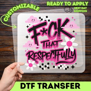 May include: A clear DTF transfer sheet featuring the black and pink text F*CK THAT RESPECTFULLY. The design includes pink smiling clouds, white and pink flowers, black and white checkered patterns, and small black star icons on a transparent background.