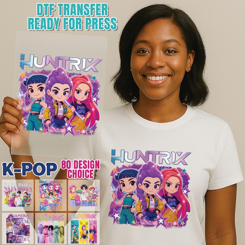 May include: A white t-shirt and a clear transfer sheet featuring a colorful cartoon graphic of three characters with the word "HUNTRIX". The transfer sheet reads "DTF TRANSFER READY FOR PRESS" and "K-POP 80 DESIGN CHOICE".