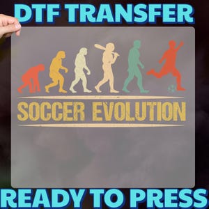 May include: DTF transfer with a "Soccer Evolution" design. The design shows a progression of figures, from ape-like to a soccer player kicking a ball. The text "DTF TRANSFER" and "READY TO PRESS" are in blue, while "SOCCER EVOLUTION" is in yellow.